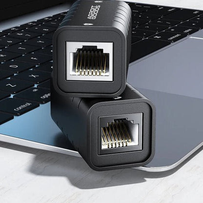 Twee zwarte netwerkkabelverlengstukken op een laptop toetsenbord geplaatst in natuurlijk licht