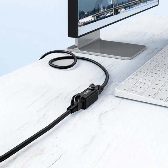 Zwarte kabel met connector aangesloten op een moderne monitor op een witte marmeren tafel