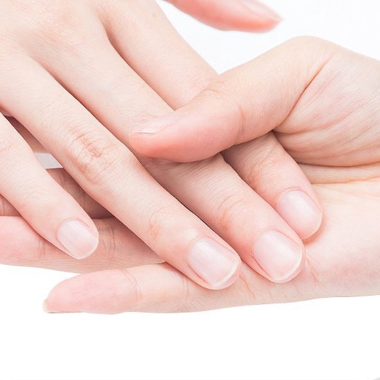 twee handen die elkaar zachtjes vasthouden op een lichte achtergrond in close-up