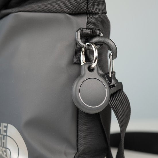 Zwarte sleutelhanger met ronde hanger bevestigd aan zwarte tas met karabijnhaak