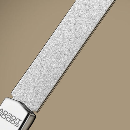 close-up van een zilverkleurige metalen riem met gegraveerd logo op een beige achtergrond