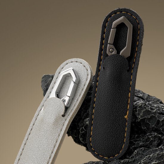 Twee stijlvolle leren sleutelhangers met metalen karabijnhaken op een donkere achtergrond