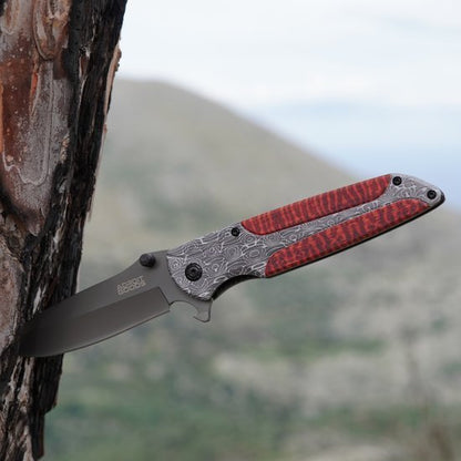 Stevig zakmes met gedetailleerd metalen handvat en rode accenten in een buitenomgeving.