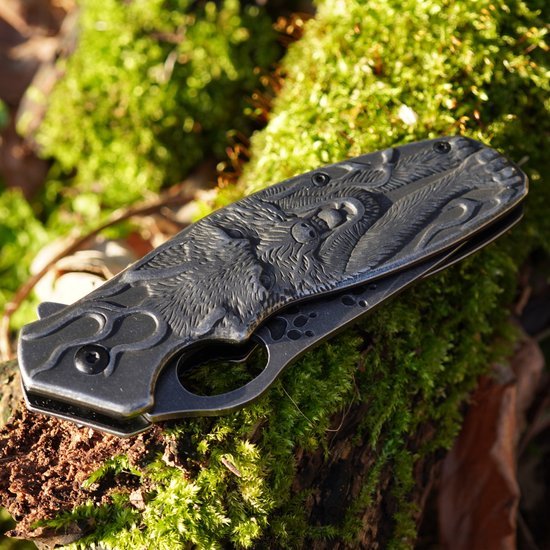 Vouwmes met gedetailleerd ingewikkeld gravuur van een vos op een groene mosachtergrond