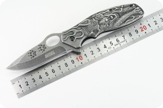 Opvouwbaar mes met gedetailleerd gegraveerd handvat en meetlat ter referentie.