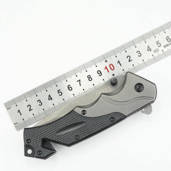 Inklapbaar zakmes met zwarte handgreep naast een liniaal voor schaalvergelijking