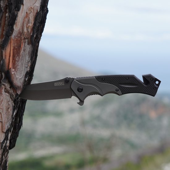 vouwmes met zwart handvat stevig vastgezet in een boomschors met onscherpe natuurachtergrond