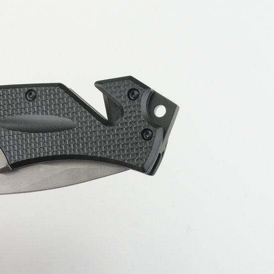 Close-up van zwart handvat met textuur en metalen mespunt in rustige achtergrond