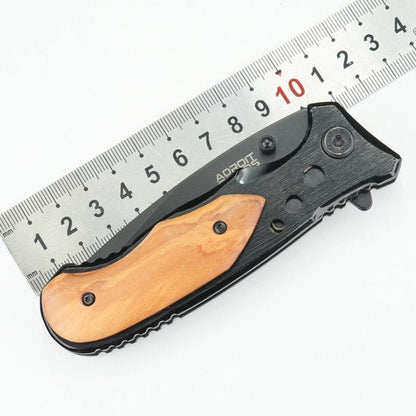 opgevouwen zwart zakmes met houten handvat en metalen liniaal op achtergrond