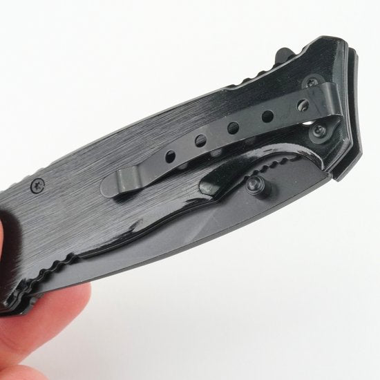 Zwarte inklapbare zakmes met riemclip en ergonomisch handvat in hand tegen witte achtergrond