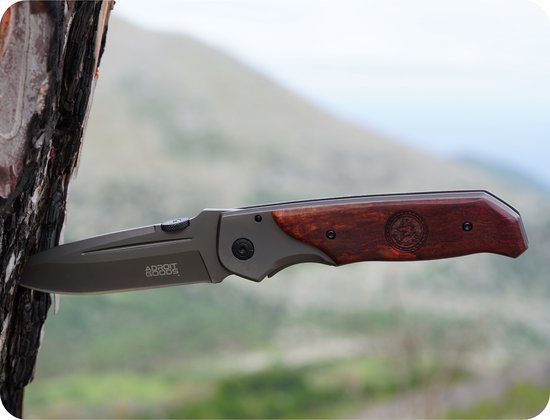 Opvouwbaar mes met metalen lemmet en houten handvat, vastgezet in boomschors buitenomgeving.