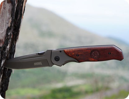 Opvouwbaar mes met metalen lemmet en houten handvat, vastgezet in boomschors buitenomgeving.