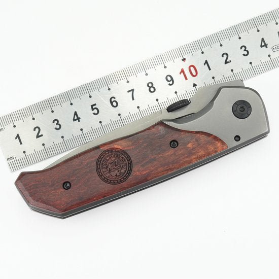 Opgevouwen zakmes met houten handgreep naast roestvrijstalen meetlat van 15 cm.