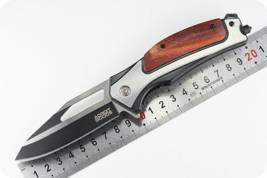 Opvouwbaar mes met zwarte lemmet en houten handvat naast een metalen liniaal.