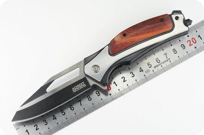 Opvouwbaar mes met zwarte lemmet en houten handvat naast een metalen liniaal.