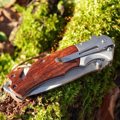 Opgevouwen zakmes met houten handvat en metalen clip, liggend op mos en boomschors.