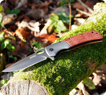 vouwmes met houten handvat en roestvrijstalen lemmet op mosbedekt stuk hout outdoors