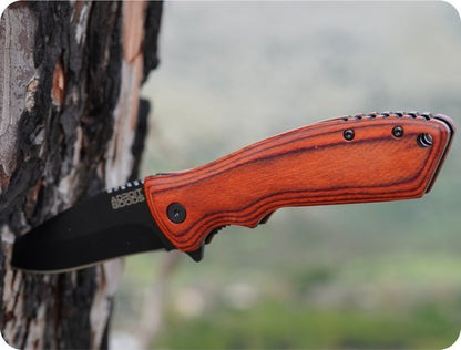 Zakmes met zwart lemmet en houten handgreep vast in een boomstam geplaatst