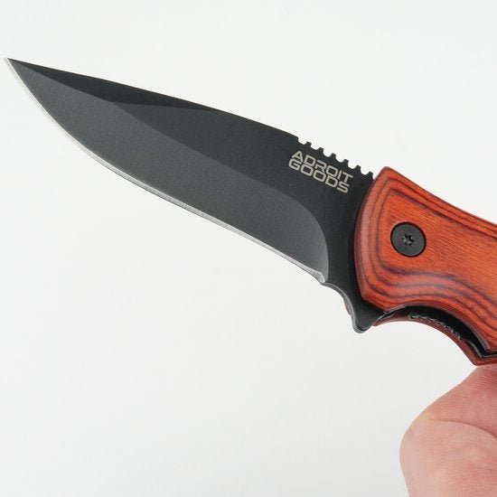 hand met mes met zwarte lemmet en houten handvat tegen witte achtergrond