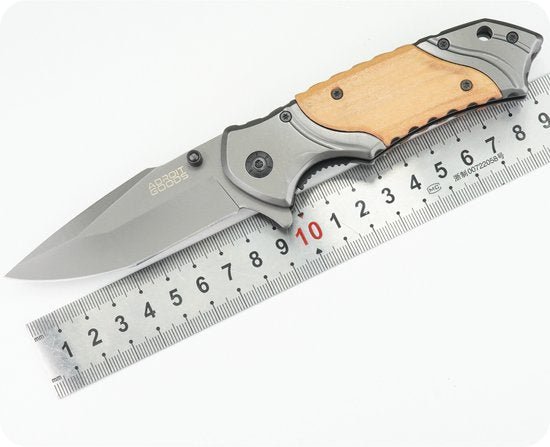 vouwmes met houten handvat en metalen lemmet naast een liniaal op witte achtergrond