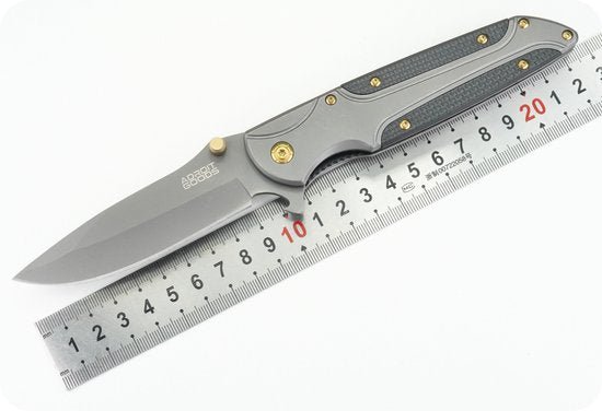 Opgevouwen zilverkleurig mes met zwarte grip ligt op een meetlat voor schaalvergelijking