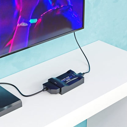 Zwart elektronisch apparaat met kabels aangesloten op een televisie op een witte tafelblad