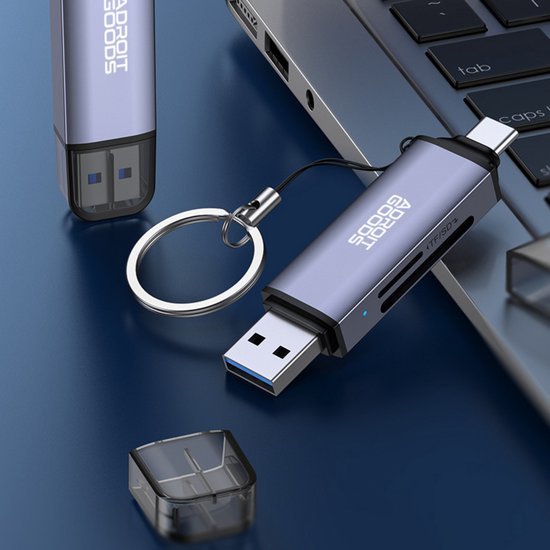 blauwe usb-stick met sleutelhanger naast laptop met open dop op blauwe ondergrond