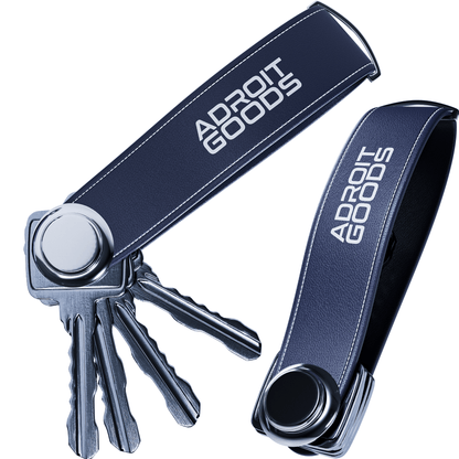 Donkerblauwe sleutelhanger met witte AdroitGoods tekst en meerdere metalen sleutels eraan bevestigd.