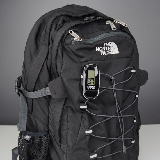 zwarte rugzak met elastisch koord en digitaal apparaat bevestigd aan de voorkant