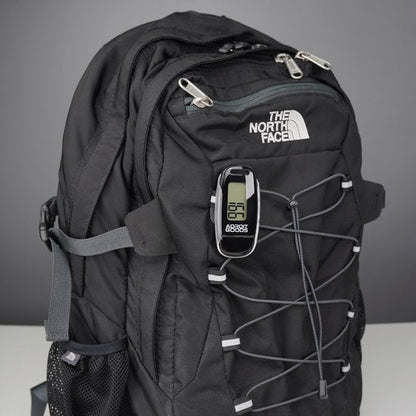 zwarte rugzak met elastisch koord en digitaal apparaat bevestigd aan de voorkant