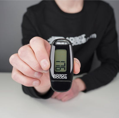 Hand houdt zwart digitaal tellertje met zichtbaar display en AdroitGoods logo vast