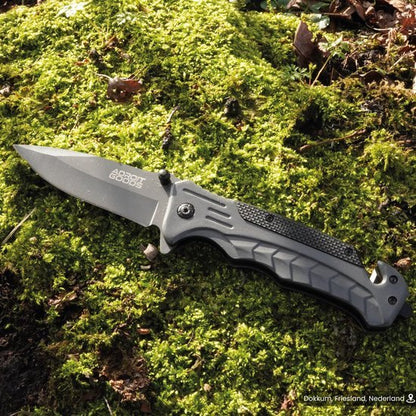 Vouwmes met zwart handvat en zilveren lemmet liggend op groen mos in de natuur