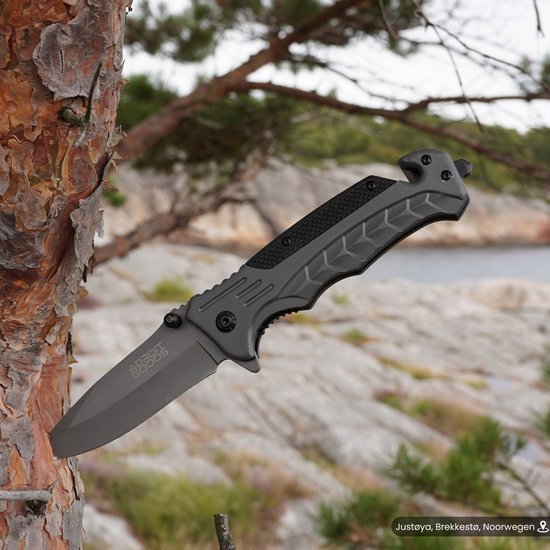 grijs inklapbaar mes met zwarte details vastgeklemd op boomschors in buitenomgeving