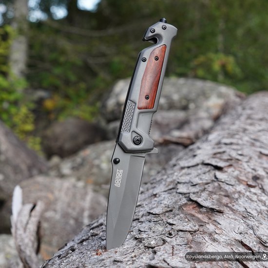 Opvouwbaar mes met houten handgreep en metalen lemmet tegen natuurlijke achtergrond