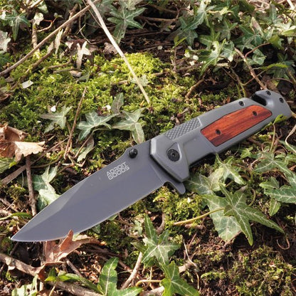 Zwart mes met houten handvat ligt op mos en klimop in een natuurlijke omgeving