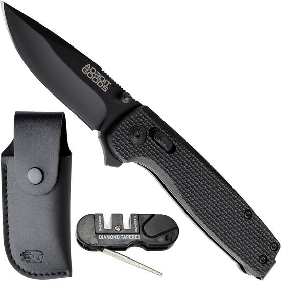 Opvouwbaar zwart zakmes met textuur handvat, leren schede en slijpsteen accessoire naast elkaar geplaatst