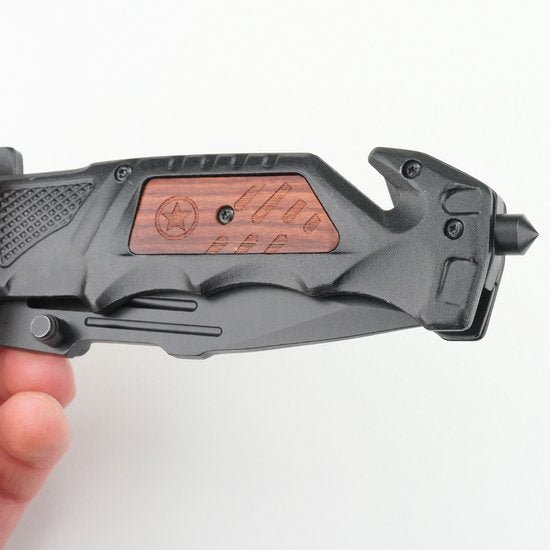 Hand die een zwarte veiligheidshamer met een houten inzetstuk en een opstaand haakje vasthoudt