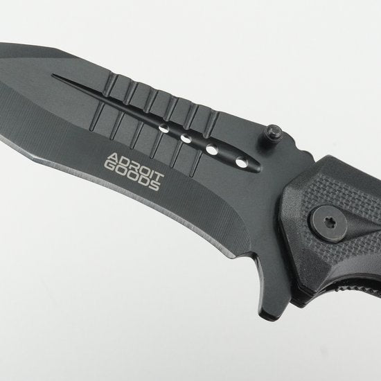 close-up van een zwart gevouwen mes met merknaam op het lemmet en een stevige handgreep