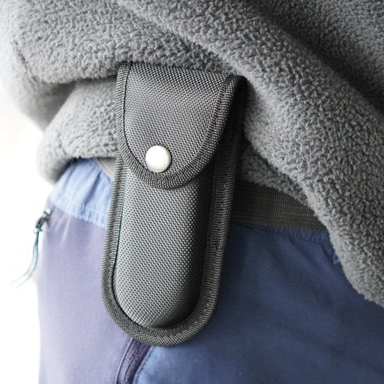 Zwarte stevige hoes met drukknop bevestigd aan grijze fleece jas en blauwe broek