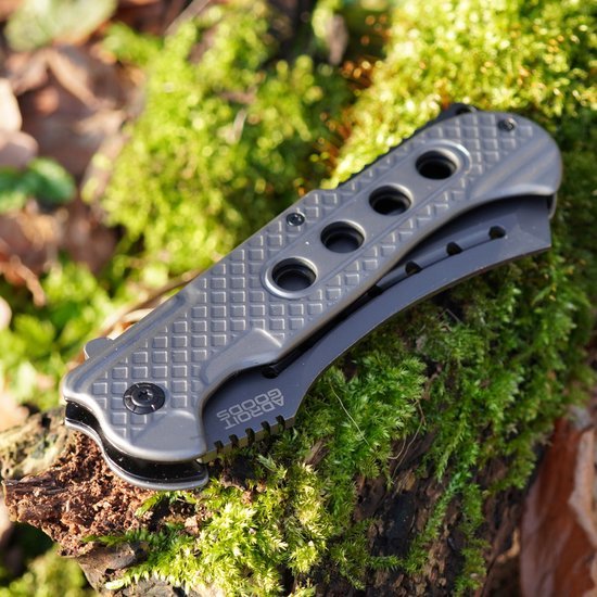 grijs zwart opvouwbaar zakmes met geperforeerd handvat op mos en hout