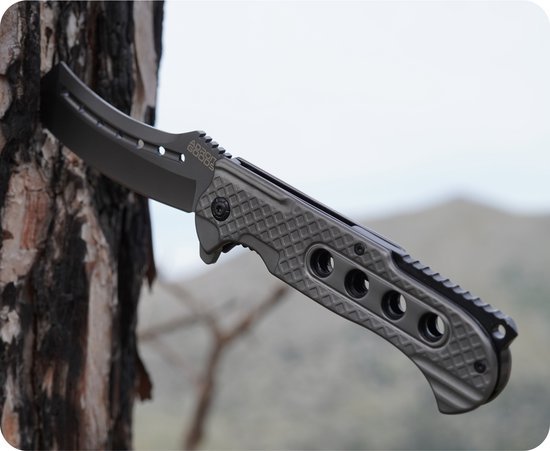 Zwart stevig mes met gegraveerd handvat en gekartelde snede in een boomstam geplaatst