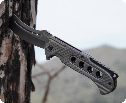 Zwart stevig mes met gegraveerd handvat en gekartelde snede in een boomstam geplaatst