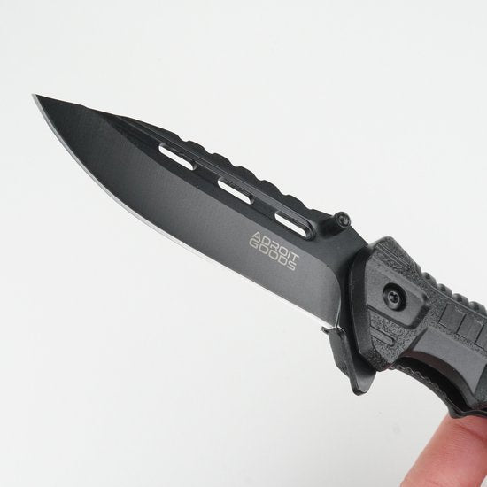 hand die zwart metalen mes met geprofileerd lemmet vasthoudt tegen witte achtergrond