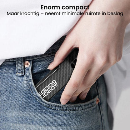 Hand die een compact zwart apparaat met witte tekst in een spijkerbroekzak steekt