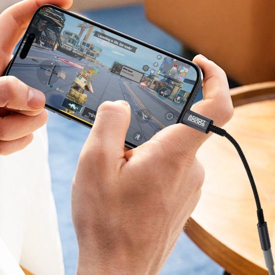Persoon speelt een schietspel op smartphone met zwarte AdroitGoods kabel verbonden aan de telefoon.