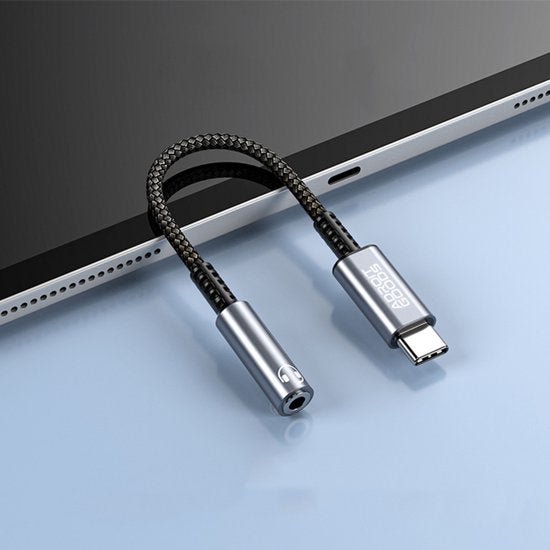 Kort zwart gevlochten kabeladapter met usb-c en audio-aansluiting naast tablet