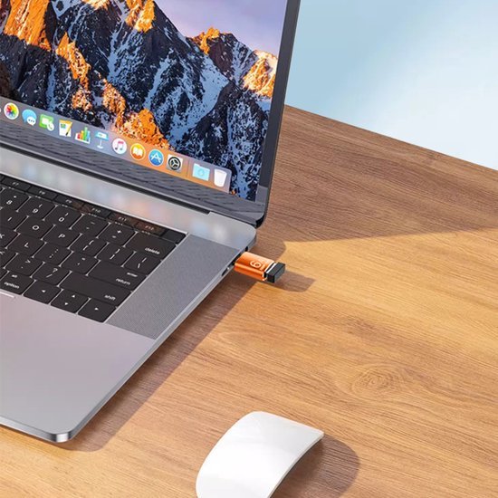 Laptop met USB-stick in poort op houten bureau naast witte muis onder natuurlijk licht