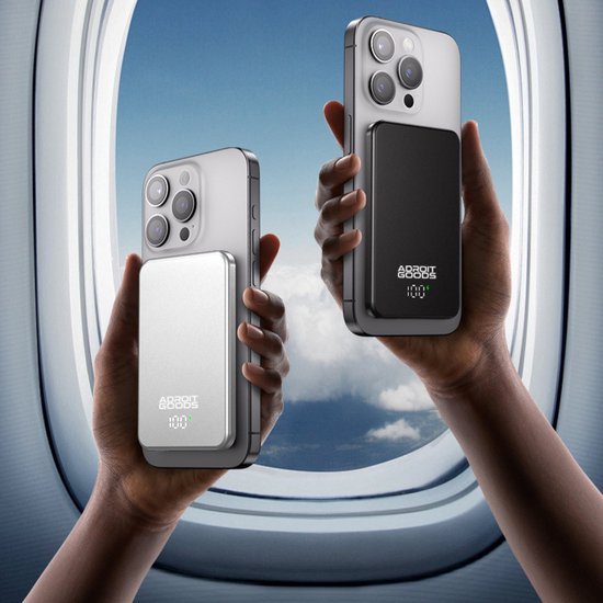 Twee handen houden telefoons vast met zwarte en zilveren powerbanks voor vliegtuigraam.