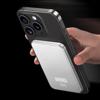 hand die een zwart telefoonhoesje vasthoudt met een zilveren draadloze oplader bevestigd