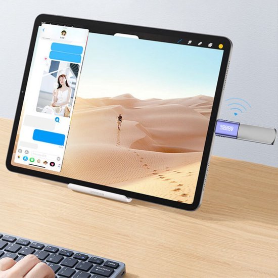 Tablet met desertfoto en USB-stick verbonden op houten bureau naast toetsenbord